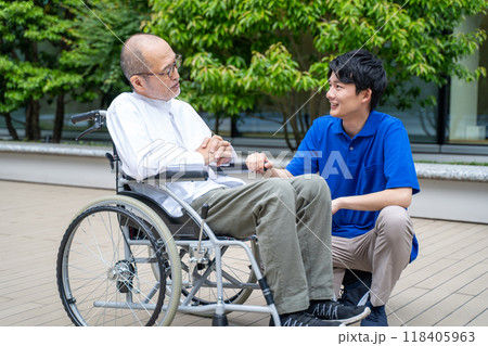 車いすのシニア男性と介護施設スタッフ 118405963