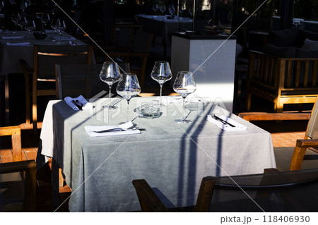 There is a table with three wine glasses and silverware set on it There is a table with three wine glasses and silverware set on it 118406930