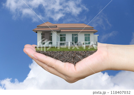 Businessman's hands with housing estate on hand and bright blue sky background. 118407032