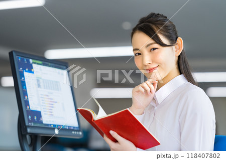 オフィスで手帳を確認する若いビジネスウーマン オフィスで手帳を確認する若いビジネスウーマン 118407802