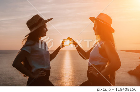 Silhouettes of Two Women Making Heart Shape at Sunset 118408156