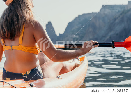 Kayaking Woman Mountains Water - A woman kayaks on a lake with mountains in the background. 118408177