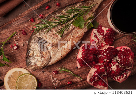 Fried dorado fish, with spices and herbs, on a wooden board, pomegranate sauce, close-up, no people, 118408621