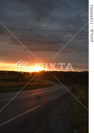 The road going into the sunset. Evening sun on the horizon and a rural road. 118409463