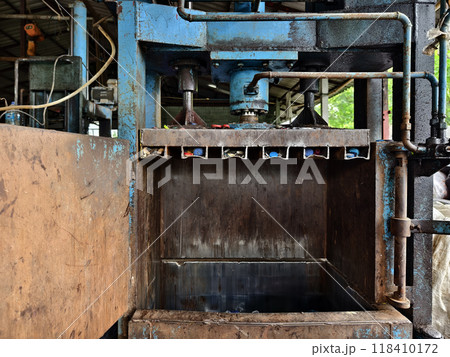 A press machine that is both dirty and rusty with its door left open 118410172