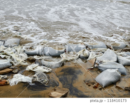 Trash scattered all over the beach close to the ocean 118410173