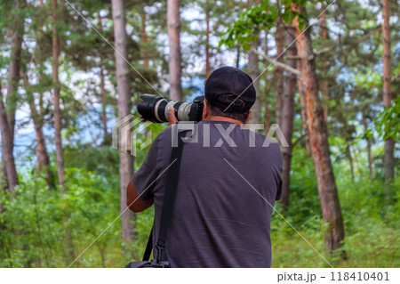 Nature photographer capturing wildlife in lush forest during daytime 118410401
