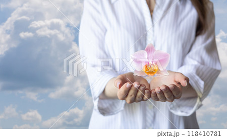 A woman tenderly holds an orchid in her hands. A woman tenderly holds an orchid in her hands. 118410781