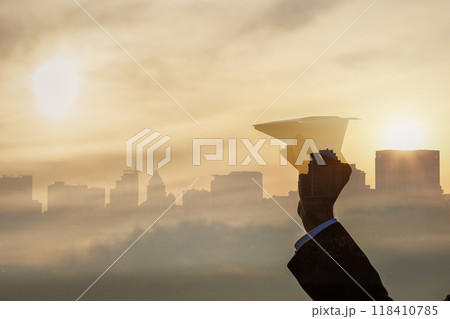 Man holding paper airplane against city skyline. Man holding paper airplane against city skyline. 118410785