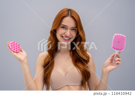 Cute young long-haired woman holding a scalp massager in hands Cute young long-haired woman holding a scalp massager in hands 118410942