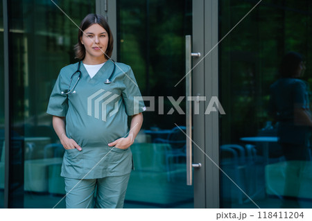 Pregnant woman in lab coat walking in front of the clinic 118411204