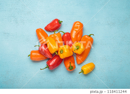 Sweet mini peppers lying on a blue tabletop Sweet mini peppers lying on a blue tabletop 118411244