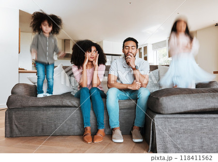 Children jumping with stressed parents on the sofa to relax in the living room of their house. Upset, burnout and excited kids playing with blur motion on couch with tired exhausted mother and father 118411562