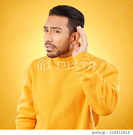 Whisper, gossip and asian man with hand on ear in studio for speak up body language on yellow background. Secret, listen and male person with hush, news or confidential coming soon promo announcement 118412918
