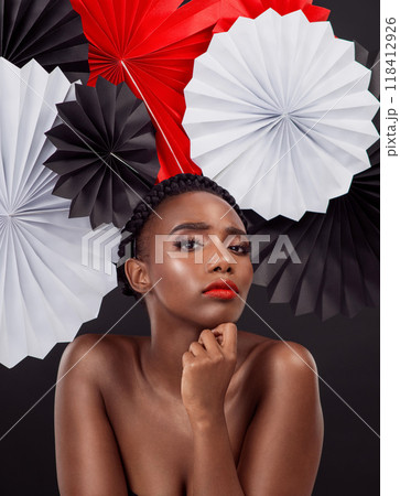 Face, makeup and black woman with origami fans in studio isolated on a dark background. Portrait, beauty cosmetics and skincare of serious female model with traditional Japanese paper hat for art. Face, makeup and black woman with origami fans in studio isolated on a dark background. Portrait, beauty cosmetics and skincare of serious female model with traditional Japanese paper hat for art. 118412926