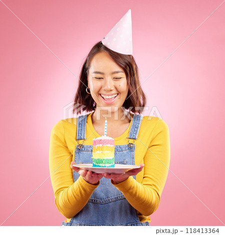 Birthday cake candle, studio and happy Asian woman excited, smile and celebrate party, present or gift. Congratulations, wow and Japanese person with dessert, candy or sweets on pink background 118413364