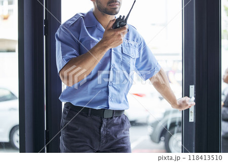 Man, radio and talking at security job in city, communication or contact for backup, support or safety in building. African protection agent, audio tech or report info in metro, cbd or door for crime 118413510