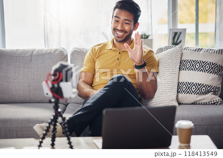 Laptop, phone and content creation, Indian man on sofa, webinar recording and live streaming in home. Internet, webcam and online influencer with smile, wave and equipment for social media channel. Laptop, phone and content creation, Indian man on sofa, webinar recording and live streaming in home. Internet, webcam and online influencer with smile, wave and equipment for social media channel. 118413549