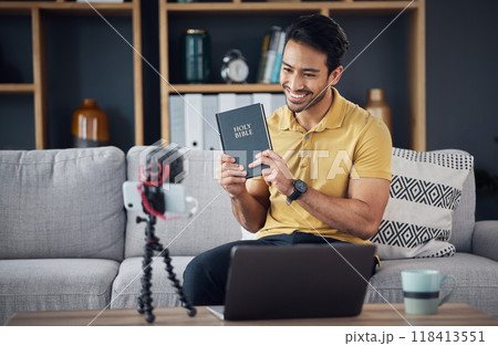 Bible, smile and man study with phone and microphone online live streaming. Asian male on home sofa with Christian religion book as blog or podcast content creator or influencer teaching or studying 118413551