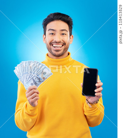 Money, online and prize with portrait and asian man in blue background with for gambling or profit. Cash, winning and guy with fintech mobile app for competition or celebration with dollar in studio. 118413829