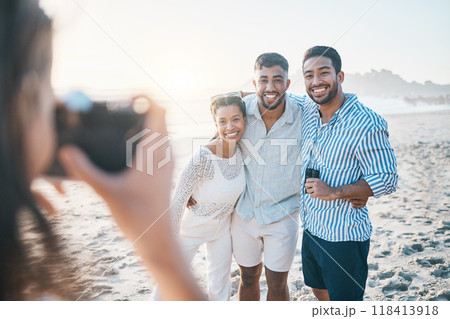 Happy, photo and friends at the beach with a photographer for summer memory, holiday or bonding. Smile, camera and a woman taking a picture of a group of people at the ocean during a vacation 118413918