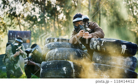 Team, paintball and tires for cover bunker or protection while firing or aiming down sights together in nature. Group of people waiting in teamwork for opportunity to attack or shoot in extreme sport Team, paintball and tires for cover bunker or protection while firing or aiming down sights together in nature. Group of people waiting in teamwork for opportunity to attack or shoot in extreme sport 118414412