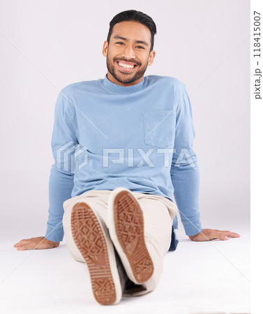 Portrait, fashion and man smile on the floor in studio isolated on a white background. Style, happy and Asian person from Cambodia in casual clothes, trendy aesthetic or confidence to relax on ground 118415007