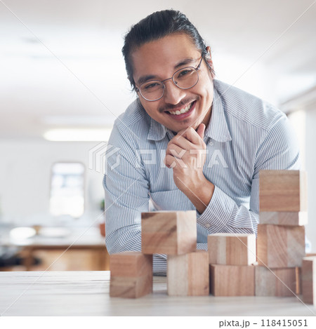 Design, strategy and portrait of man with building blocks in office, thinking and innovation for balance with smile. Engineering, challenge and asian designer with wood block game for problem solving 118415051