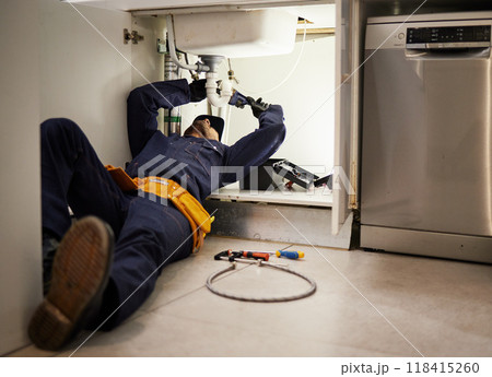Kitchen, maintenance and renovation with a plumber on the floor of a home to fix a leak, issue or problem. Plumbing, repair and tools with a handyman or contractor working on a pipeline in a house Kitchen, maintenance and renovation with a plumber on the floor of a home to fix a leak, issue or problem. Plumbing, repair and tools with a handyman or contractor working on a pipeline in a house 118415260