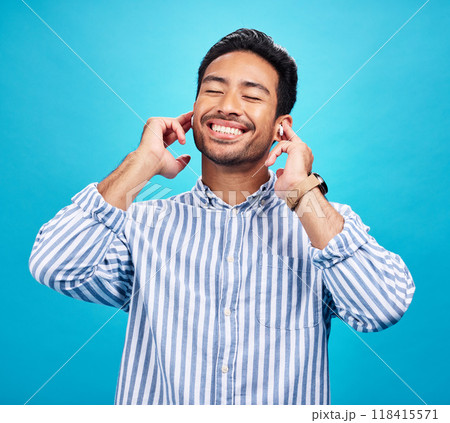 Happy man, earphones and and music in studio, relax and cheerful on blue background. Radio, smile and indian male smile while listening to podcast, streaming or audio, online or subscription isolated 118415571