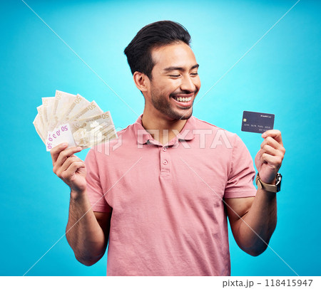 Smile, money and credit card by happy man in studio with savings, finance or investment growth on blue background. Cash, joy and asian guy excited for banking, success or financial freedom isolated Smile, money and credit card by happy man in studio with savings, finance or investment growth on blue background. Cash, joy and asian guy excited for banking, success or financial freedom isolated 118415947