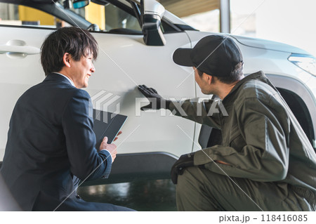 車の傷・凹みを確認する整備士の男性とスーツ姿のセールスマン 118416085