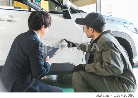 車の傷・凹みを確認する整備士の男性とスーツ姿のセールスマン 118416086