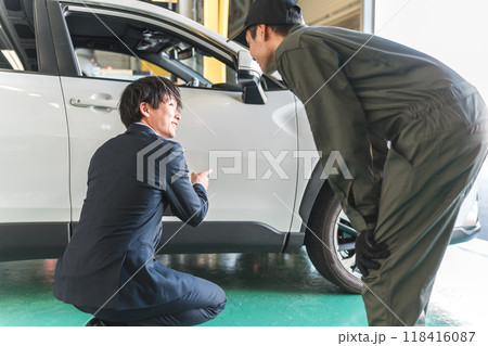車の傷・凹みを確認する整備士の男性とスーツ姿のセールスマン 118416087