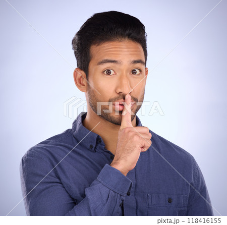 Man, portrait and finger on lips for secret, gossip or silence in studio with blue background. Face of a asian model person with hand on mouth for emoji sign to surprise, hush or quiet for privacy 118416155