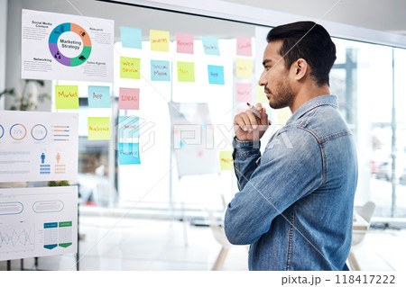 Creative man, thinking and glass board for project management, marketing or planning at office. Male person, manager or employee checking project plan, tasks or statistics for startup at workplace 118417222