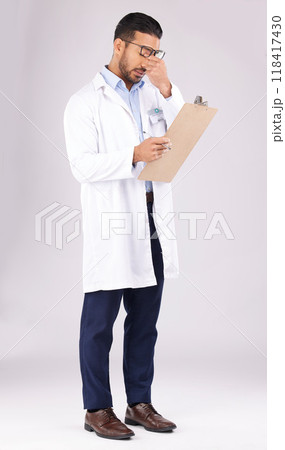 Burnout, clipboard and man doctor in a studio for a medical diagnosis or wellness treatment. Stress, headache and male healthcare worker with a migraine for checklist isolated by a gray background. 118417430