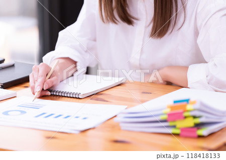 Hand of a businesswoman working with papers and documents at a desk in the office. Hand of a businesswoman working with papers and documents at a desk in the office. 118418133