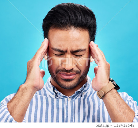 Man with headache, pain and stress with anxiety and mental health problem or crisis isolated on blue background. Male person hands holding head, massage temple with depression and migraine in studio 118418548