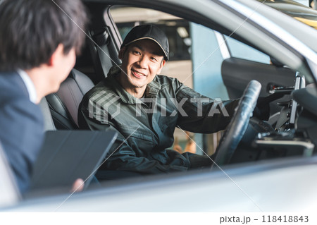 車の中でフロントマンの男性と会話する整備士の男性 118418843