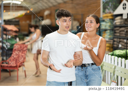 Married couple look for something in room garden furniture store, searching for item to complete patio. Woman with husband buyers looks around in showroom Married couple look for something in room garden furniture store, searching for item to complete patio. Woman with husband buyers looks around in showroom 118419491