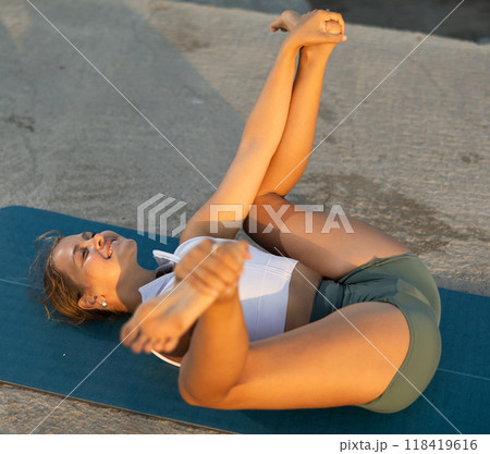On windy day young slender woman does yoga near sea doing practicing hatha yoga 118419616