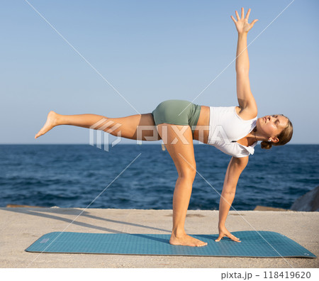 Athletic girl meditates in a yoga pose parshvottanasana on seashore Athletic girl meditates in a yoga pose parshvottanasana on seashore 118419620