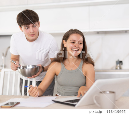 Young guy smiling and chatting with woman working at laptop Young guy smiling and chatting with woman working at laptop 118419665