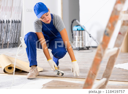 Young female builder puts laminate flooring 118419757