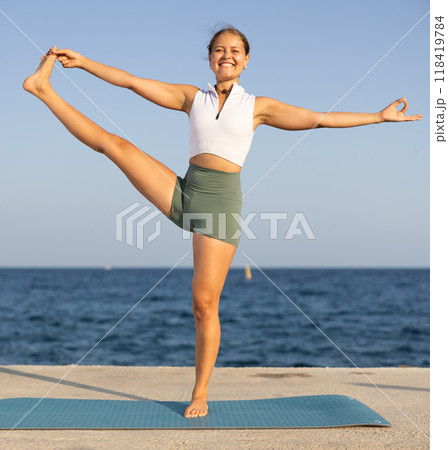 Sportive girl practicing extended hand to toe pose of yoga on seashore Sportive girl practicing extended hand to toe pose of yoga on seashore 118419784