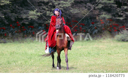 BELARUS,DUDUTKI - JULY 29, 2018: MEDIEVAL FESTIVAL. Lady in a maroon opland riding a brown horse 118420773