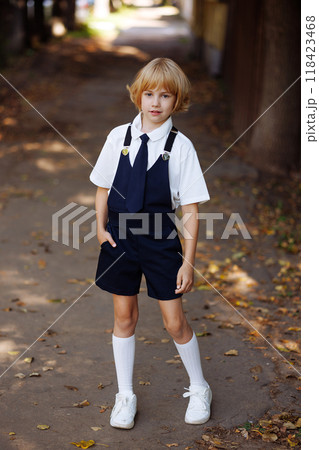 Young schoolgirl in school uniform standing on the sidewalk. Back to school. Young schoolgirl in school uniform standing on the sidewalk. Back to school. 118423468