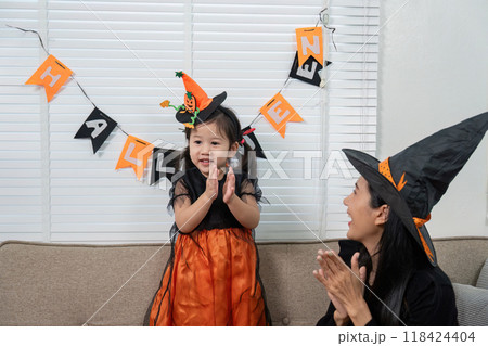 Mother and Daughter Celebrating Halloween with Costumes and Decorations at Home 118424404