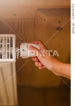 a woman's hand setting the room temperature By Thermostat in wooden house. High quality photo a woman's hand setting the room temperature By Thermostat in wooden house. High quality photo 118424721